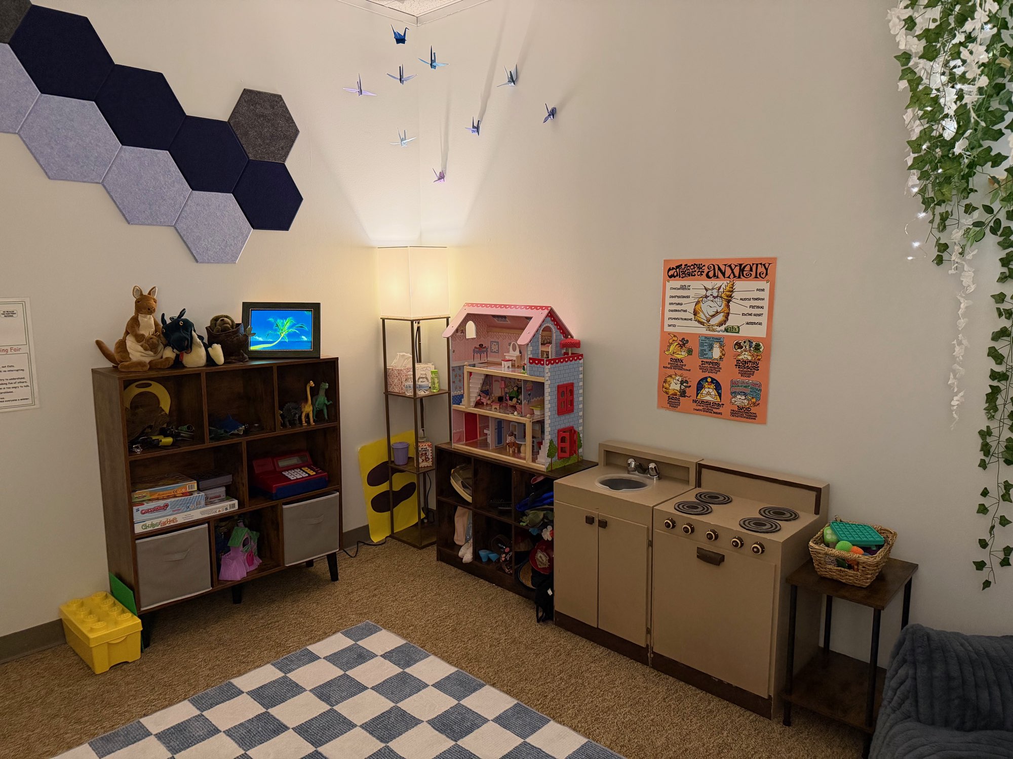 Play kitchen, dollhouse, stuffed animals, and toy shelves in the play therapy room