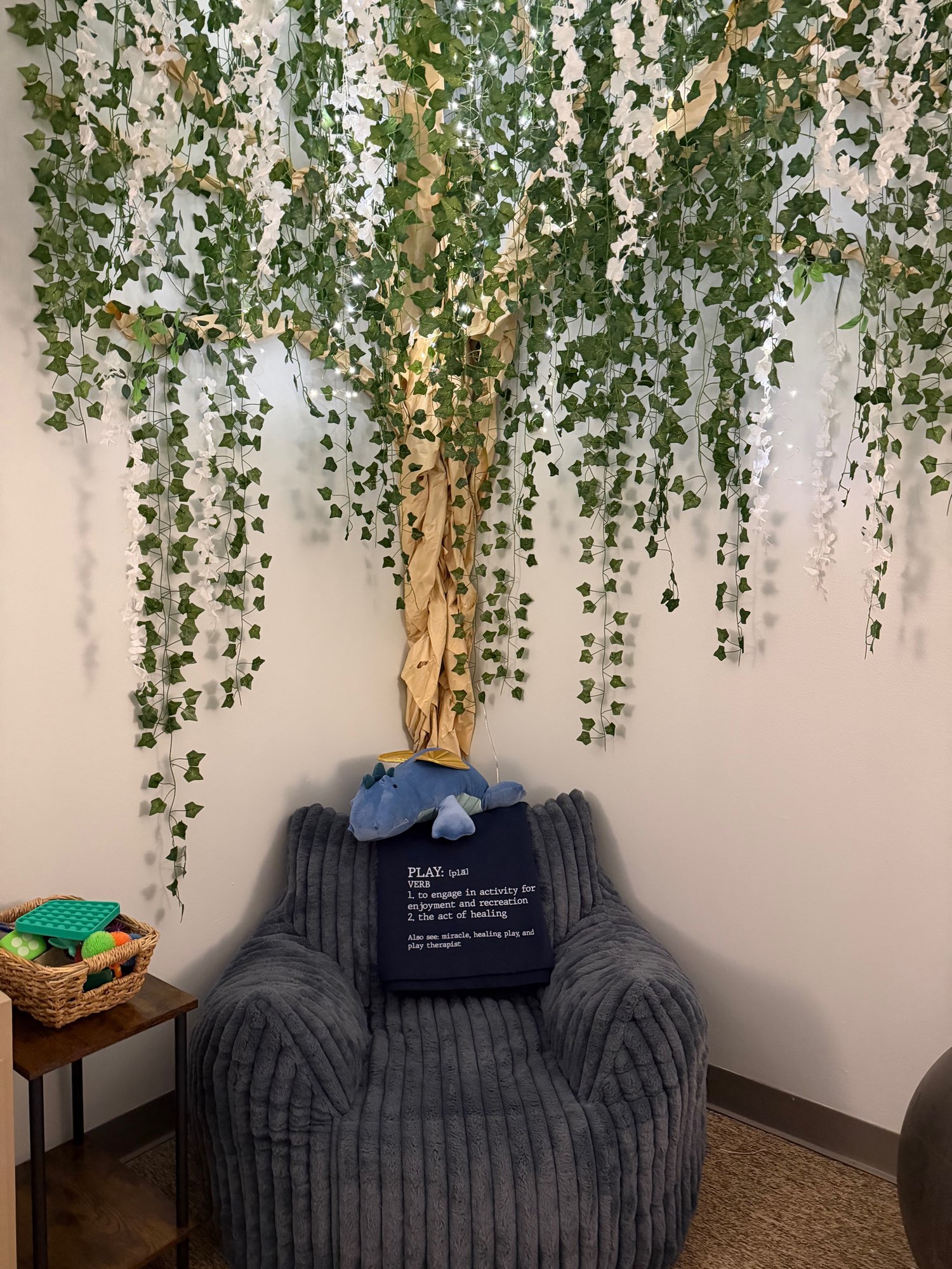 Cozy corduroy chair beneath a tree of hanging vines and twinkle lights